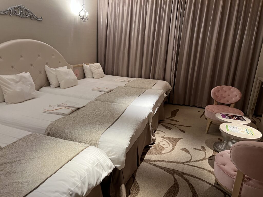 Spacious family room at Hotel Universal Port Vita in Osaka with three beds and a pink chair.