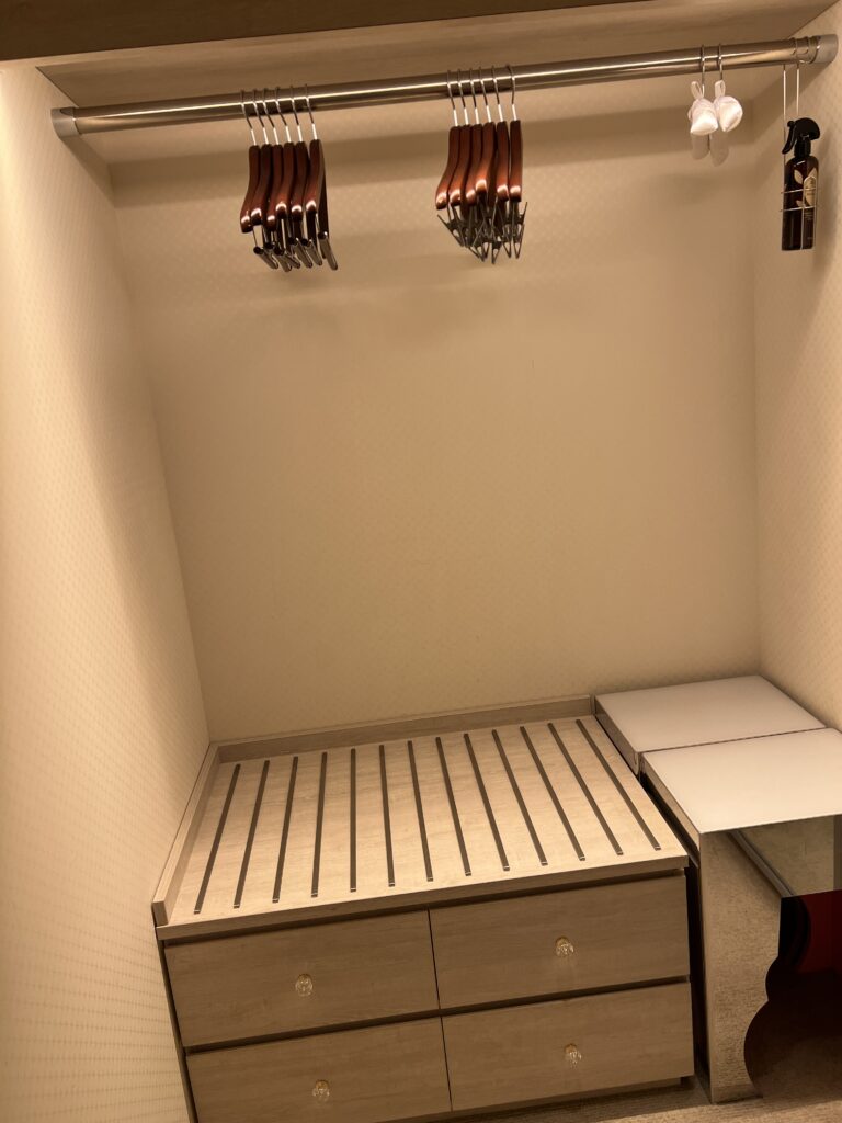 Walk-in closet at Hotel Universal Port Vita with hangers and shelves, offering plenty of space for suitcases and clothes.