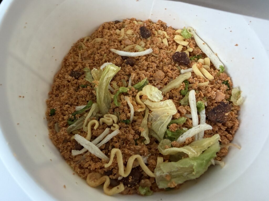 Inside the Spicy Miso-Kin cup before adding hot water, showing dry noodles, minced meat, cabbage, and other ingredients.