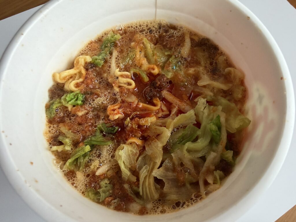 Spicy Miso-Kin ramen after adding hot water and chili oil, with vibrant red broth bubbling at the surface.