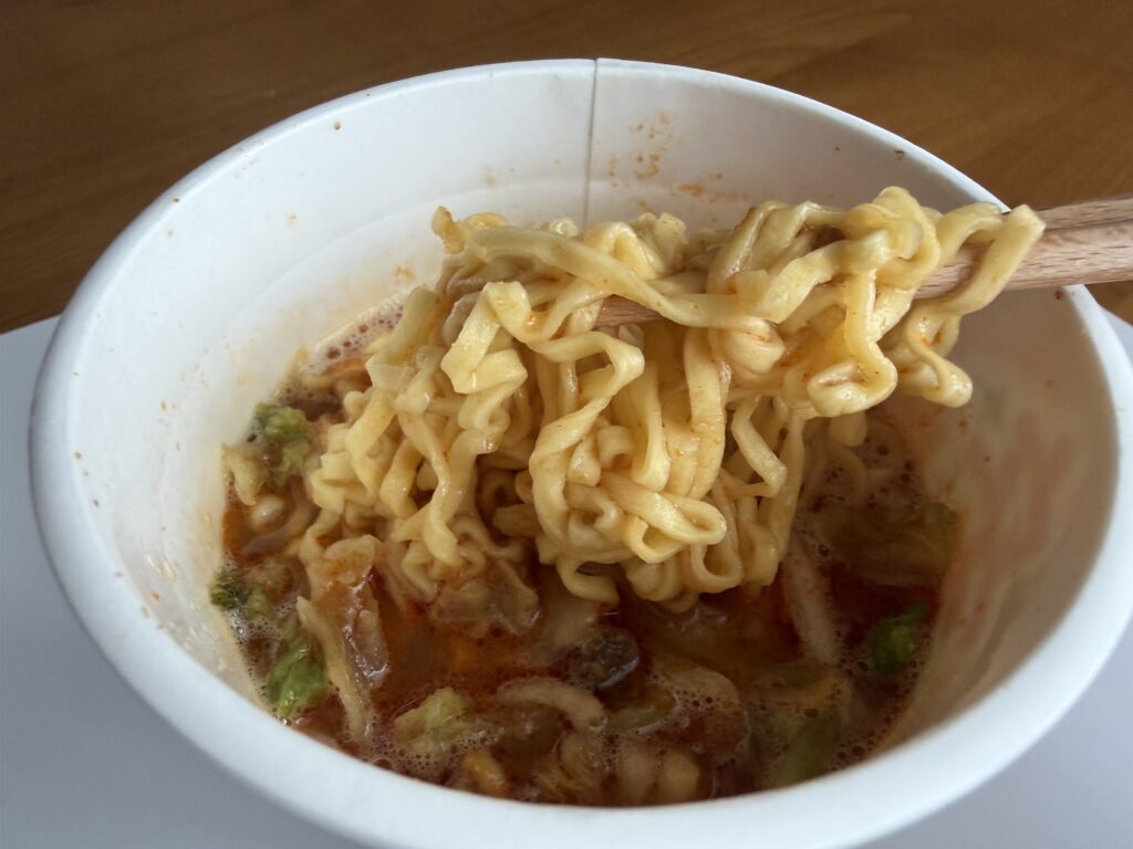 完成した辛みそきんを箸で持ち上げた様子。太麺に濃厚な辛味噌スープがよく絡んでいる。