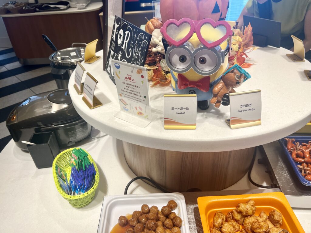 Cute Minions figurine decorating the kids’ buffet section at Hotel Universal Port Vita, surrounded by meatballs, fried chicken, and colorful autumn items.