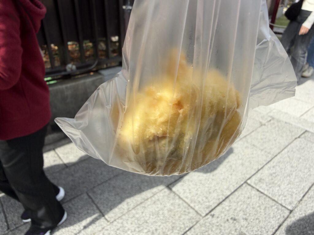 A fried manju from Asakusa Kokonoe in a plastic takeout bag, ready for eating while walking around Asakusa.