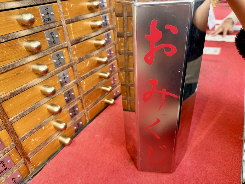 A silver hexagonal omikuji box with red Japanese characters used for shaking out fortune sticks at Senso-ji Temple.