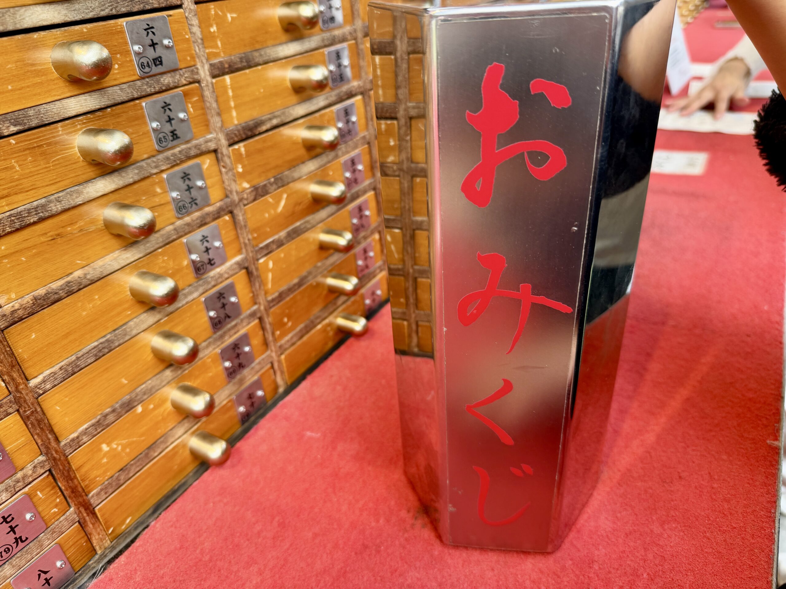 A silver hexagonal omikuji box with red Japanese characters used for shaking out fortune sticks at Senso-ji Temple.