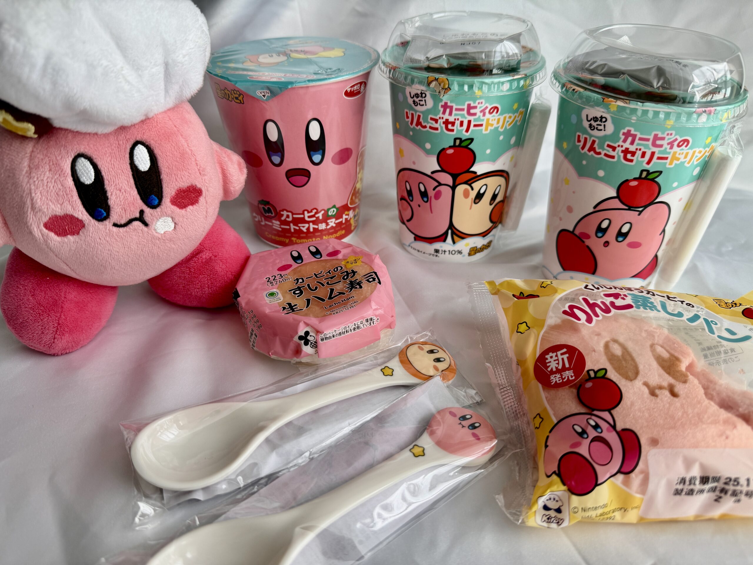 ファミマ×カービィ第1弾の全商品とスプーン特典を並べた写真。くいしんぼうカービィのぬいぐるみとコラボフード4種。